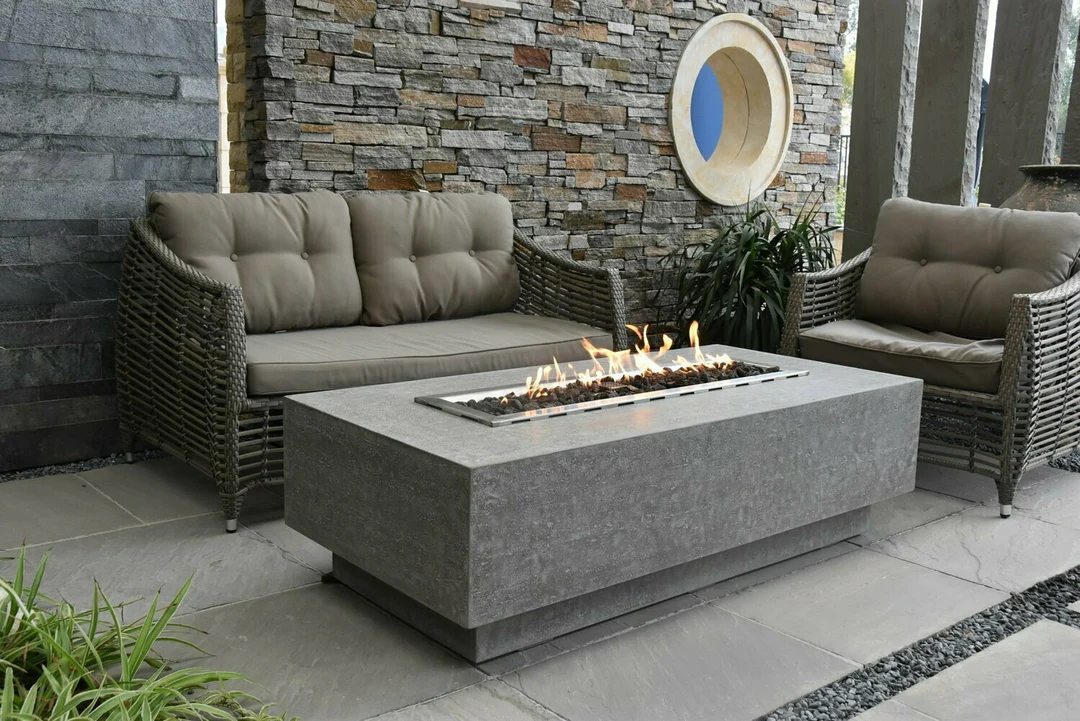 Rectangular linear fire table with stone wall backdrop